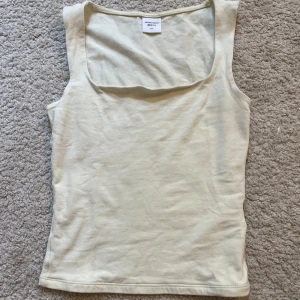 Gul linnetopp från Gina Tricot - Snygg beige linnetopp från Gina Tricot med fyrkantig ringning och ärmlös design. Toppen har en figurnära passform som sitter tajt mot kroppen. Nypris: 150kr. Storlek: xxs. Använd fåtal gånger.  Skriv privat om frågor 💕
