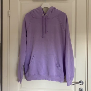 Ljuslila hoodie med huva och ficka - En oversized ljuslila hoodie med huva och dragsko, samt en stor magficka. Tröjan har långa ärmar och är tillverkad i mjuk bomullsblandning. Perfekt för mysiga dagar och chill outfits. Det är två små hål men det är inget som syns o inget någon tänker på!