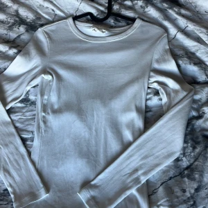 Vit långärmad tröja från Gina Tricot - Säljer en vit långärmad tröja från Gina Tricot, basically basics-kollektionen. Tröjan är i mycket bra skick och har en fin passform med rund halsringning. Perfekt som basplagg och enkel att styla till olika outfits.
