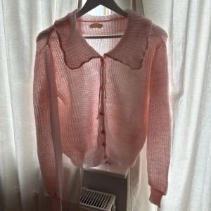 Söt rosa vintage kofta  - En superfin ljusrosa vintage stickad kofta och knappar framtill. Koftan har långärmad passform och är gjord i ett tunt, transparent stickat material . Perfekt att slänga över en topp för en gullig look. Små tecken på användning vid knapphål och koftan passar storlek S