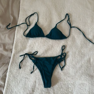 Mörkblå trekantsbikini med knyt - Säljer en stilren mörkblå bikini med trekantsöverdel och knyten på både över- och underdelen. Klassisk modell med smala band och enkel design, perfekt för stranden eller poolen. Materialet är mjukt och skönt 💓Båda delar är självklart nytvättade :) 