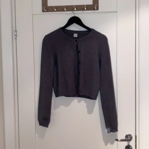 Mörkgrå kofta från Lindex - Mysig mörkgrå kofta från Lindex med rund halsringning och knappar framtill. Långärmad och i stickad kvalitet, perfekt för lager på lager. Säljer tröjan för att den är för liten och att jag aldrig har använt den 