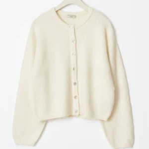 Vit kofta med knappar från H&M - Supermjuk och fluffig vit kofta från Gina med rund halsringning och pärlemorskimrande knappar framtill. Pris kan diskuteras!