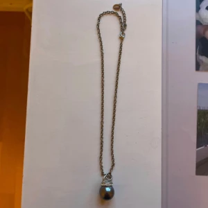 Silverhalsband med pärlhänge från Snö - Snyggt silverfärgat halsband med en kedja och ett droppformat pärlhänge. Hänget har en rad små glittriga stenar upptill som ger extra bling. Perfekt för dig som gillar stilrena smycken med en twist.