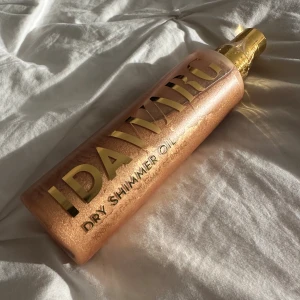 Ida Warg Dry Shimmer Oil  - Glittrande torr shimmerolja från Ida Warg i en lyxig guldig-bronsig nyans. Oljan ger huden en snygg glow och doftar sommar. Helt ny med plombering/plasten kvar 