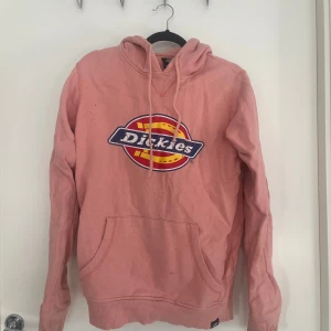 Rosa hoodie från Dickies  - Säljer en rosa hoodie från Dickies i storlek XS men skulle säga att den sitter mer som S då den är lite större i storleken. Tröjan har stor logga framtill, huva med snörning och en klassisk känguruficka. 