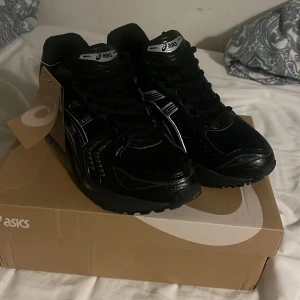 Svarta sneakers - Säljer ett par svarta sneakers med silvriga detaljer. Skorna har mesh och syntetmaterial, klassisk snörning och en sportig vibe. Perfekta för dig som gillar streetstyle och bekväma skor med cool design.