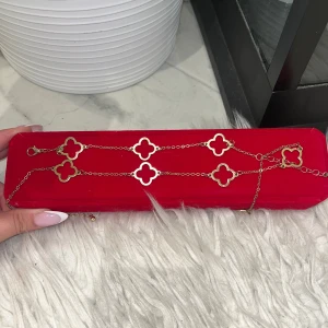 Guldigt armband med fyrklöver - Snyggt armband i guld med flera fyrklöverformade länkar. Kedjan är tunn och elegant, och de öppna klöverdetaljerna ger en cool och modern vibe. Perfekt för dig som gillar stilrena smycken med en twist. Lätt att matcha med andra accessoarer. Boxen är inte med