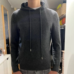 Merinoull hoodie - Mörkgrå merinoull hoodie perfekt till kalla hösten o vinter. Är knappt använd och är i toppskick. Inga nopprar pch storlek M. Modellen är 188cm lång och väger ca 70kg. Skriv om du har frågor eller funderingar!