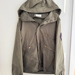 Olivgrön jacka från Saint Laurent - Säljer en olivgrön jacka från Saint Laurent.                                 Jackan är i storlek 46 vilket motsvarar S passar även större.                                                                    Den är i väldigt bra skick har bara använt den över vintern som en chill jacka.                    Jackan är köpt på ILLUM i Danmark har kvitto/äkthetsbevis på den🍾