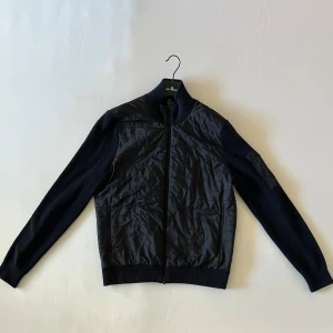  J.Lindeberg grich jacka M - En JLindberg mörkblå jacka perfekt  för kalla tider. Storleken är M men kan fungera L. Den är i bra skick men lite nopprig vilket går att ta bort! 