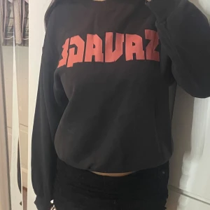 Svart sweatshirt med röd SAVAGE-tryck - Cool svart sweatshirt med stort rött SAVAGE-tryck på bröstet. Tröjan har rund halsringning, långa ärmar och ribbade muddar vid ärmslut och nederkant. Perfekt för en avslappnad streetstyle-look.