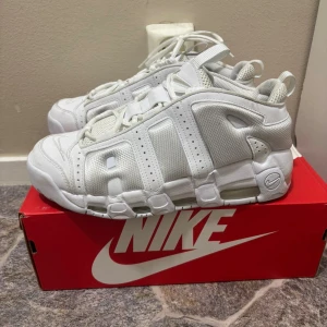 Nike Air More Uptempo vita sneakers - Säljer ett par feta Nike Air More Uptempo sneakers i helvitt. Skorna har en chunky siluett med stora AIR-bokstäver på sidan, snörning och meshdetaljer för extra ventilation. Perfekt för dig som gillar retro vibes och streetstyle.