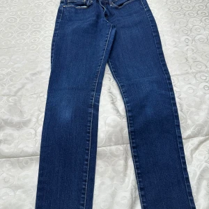 Mörkblå raka jeans från Levi's - Snygga mörkblå jeans från Levi's med klassisk femficksdesign och raka ben. Jeansen har normal midja och är tillverkade i slitstarkt denimtyg som ger en tidlös look. 