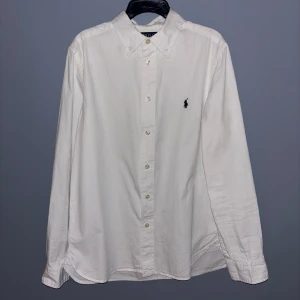 Vit skjorta från Ralph Lauren - Vit skjorta från Polo Ralph Lauren mad svart logotyp på bröstet. Skulle passa bra mellan längderna 168-173 cm.