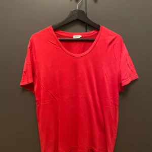 Röd t-shirt från Filippa K - Enkel och stilren röd t-shirt från Filippa K med rund halsringning och korta ärmar. Tillverkad i mjuk bomull som känns skön mot huden. Perfekt att matcha med jeans eller shorts för en clean look.