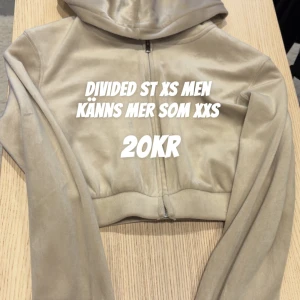 Beige croppad hoodie från Divided - Snygg beige croppad hoodie från Divided med dragkedja framtill. Jackan har lång ärm och är tillverkad i ett mjukt, mockaliknande material. Perfekt för dig som gillar en tight och trendig look.