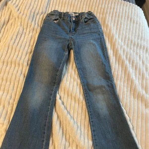 Lager 157  blå jeans, storlek 140 - Säljer ett par Lager 157  jeans i blå tvätt med bootcut-ben. Byxorna har fem fickor, knapp och dragkedja framtill samt snygga kontrastsömmar. Perfekt passform och cool retrostil för dig som gillar tidlösa jeans.