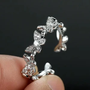 Silverring med fjärilar och stenar - Superfin silverfärgad ring dekorerad med flera små fjärilar och gnistrande stenar. Ringen har en öppen design och fjärilarna är detaljerade med små glittrande stenar som ger en lyxig känsla. Perfekt för dig som gillar unika och söta accessoarer.