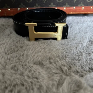 H bälte svart/guld - Använt skick. Några av hålen är lite uttöjda och spännet har några små repor annars är den bra. Fraktas inom 48 timmar.