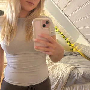 Ljusgrå tight topp med öppen rygg - Säljer en ljusgrå, tight topp med korta ärmar och öppen i ryggen. Normal i storleken och använd några gånger 