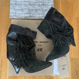 Svarta boots med fransar Isabel Marant x H&M - Svarta boots från Isabel Marant pour H&M med coola fransdetaljer på sidorna. Skorna har spetsig tå, hög klack och är tillverkade i en mix av mocka och skinn. Perfekt statement-piece med snyggt vikt skaft och unik design.