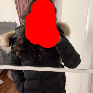 pufferjacka från Hollies - Säljer en svart pufferjacka från Hollies med snyggt bälte i midjan och RIKTIG päls på huvan. Jackan har dragkedja framtill, två bröstfickor med dragkedja och  leopardmönstrat foder. Har tecken på användning därav priset!! PRISET kan diskuteras