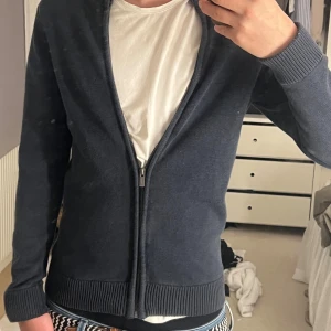 Mörkblå stickad kofta med dragkedja - Snygg mörkblå stickad kofta med hel dragkedja framtill och ribbade muddar vid ärmslut och nederkant. Perfekt för lager-på-lager och funkar året runt. Enkel och stilren design som passar till det mesta. Jag är 184 och 72 kg. Tröjan är av märke ”Dobber” och är i storlek S. Skriv om du har frågor eller om du vill diskutera pris!