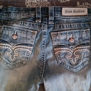 Rock Revival jeans - Säljer ett par sjukt snygga rock revival jeans, köpta på vinted för 1000kr men har aldrig använt då de inte passade mig samt var för långa🥲. De är i bra skick men har lite slitningar, personligen tycker jag det gör dem snyggare❤️ Midjemåttet rakt över:40cm. Innrebenslängden är ca:82cm. Pris kan diskuteras🫶 Var inte blyg att kontakta mig vid frågor💕
