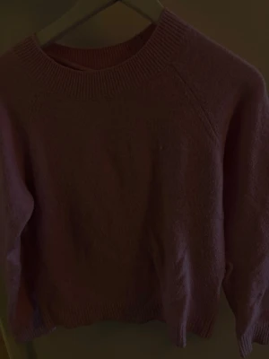 Rosa stickad tröja - Mysig rosa stickad tröja med rund halsringning och ribbade muddar vid ärmslut och nederkant. Tröjan har en enkel och stilren design, perfekt att matcha med jeans eller kjol. Materialet känns mjukt och passar bra för kyligare dagar.