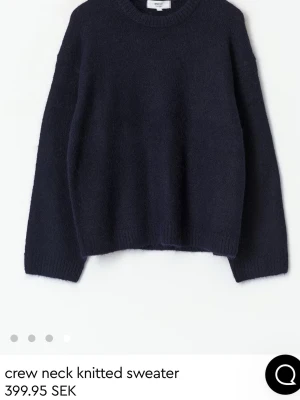 Mörkblå stickad tröja Gina  - Mysig mörkblå stickad tröja från Gina med rund halsringning och långa ärmar. Tröjan har en enkel, rak passform och ribbade muddar vid ärmslut och nederkant. Perfekt för lager på lager under kyliga dagar.