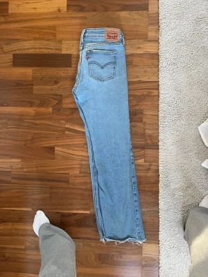 Levi's Superlow Bootcut jeans ljusblå - Ljusblå Levi's Low Bootcut jeans i klassisk femficksmodell med låg midja och bootcut-ben. Jeansen har slitna detaljer och fransad nederkant, tillverkade i mjukt bomullsdenim. Passar mig som bör storlek 36 i jeans bland annat 