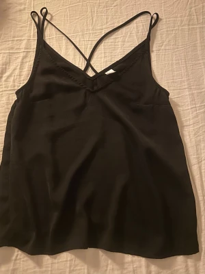 Fest linne - Säljer en svart linnetopp i storlek 36 med tunna axelband som korsas i ryggen. V-ringad enkel fest linne!💗
