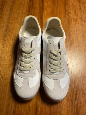 Maison margiela gats - Helt nya Maison margielas som är vita o beige i storlek 43 men är snarare storlek 42. Skorna är otroligt stilrena. Det ingår inpackningspapper, Dustbag.
