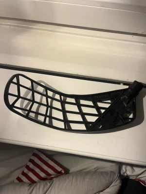 Svart innebandyblad plast. Märke EXEL - Säljer ett svart innebandyblad i plast med ett öppet rutmönster. Bladet har en böjd form och passar till de flesta innebandyklubbor. Perfekt för dig som vill byta ut eller uppgradera bladet på din klubba.