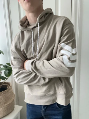 Zadig & Voltaire hoodie  - Zadig & Voltaire hoodie i storlek L i färgen beige med tre vita ränder och en Voltaire text på ryggen. Inga defekter! Hur najs hoodie som helst som bara är lite stor på modellen som är 180 cm 75 kg. Kom med frågor! 