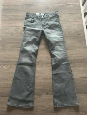 Grå bootcut jeans från Lager 157 - Snygga grå jeans från Lager 157 med klassisk bootcut passform. Jeansen har fickor både fram och bak, med låg midja och utsvängda ben. Perfekta för dig som vill ha en snygg och cool look.