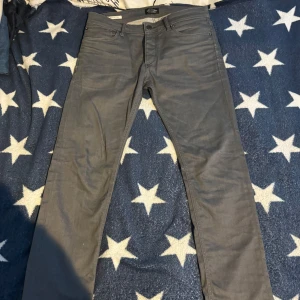 Gråa jeans från Jack & Jones - Snygga gråa jeans från Jack & Jones med klassisk femficksdesign och raka ben. Jeansen har normal passform och är tillverkade i mjukt bomullsmaterial med lite stretch för extra komfort. Perfekta till en avslappnad stil.