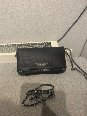 Zadig&Voltaire väska - Mitt ex har lämnat kvar sin väska här för ett halvår sen så nu säljer jag den. Fås med både långt och kort axelband och väskan är i nyskick