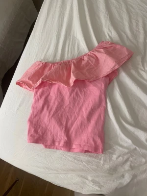 Rosa oneshoulder topp från Kappahl - Säljer en jättesöt rosa oneshoulder topp från Kappahl med volangdetalj längs axeln!! 💞💞ej använd så mycket!!💞