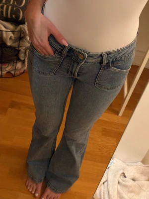 Blå bootcut jeans med låg midja - Säljer ett par ljusblå jeans med bootcut-modell och låg midja. Klassisk femficksdesign och snygga sömmar på bakfickorna. Jeansen har en avslappnad passform och är tillverkade i mjukt denimtyg. Perfekta till sneakers eller boots. 