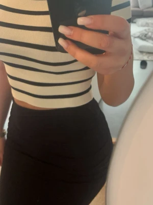 Randig croppad topp i ribbad bomull och lånh svart kjol - Säljer en croppad topp med svarta och vita horisontella ränder. Toppen är ribbad och har korta ärmar. Och en ankel lång kjol (tröja 50kr) (kjol 90kr)