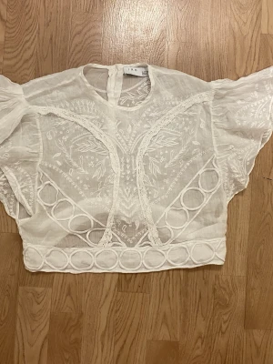 Cute white blouse with intricate lacy details all over and button closure inte the back - Jättegullig blus från IRO med söta detaljer både bak och fram och knappar baktill.  Finns ett litet hål vänster fram, men det synts knappt och går att fixa enkelt med ett eller två stygn!🥰