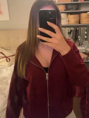 Vinröd hoodie med dragkedja - Mysig vinröd hoodie med dragkedja framtill och huva. Modellen är enkel och stilren, perfekt att slänga på sig över en t-shirt. Materialet känns mjukt och skönt mot huden. Passar dig som gillar en avslappnad och chill stil.