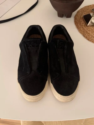 Svarta slip-on sneakers från Eytys - Svarta slip-on sneakers från Eytys med tjock vit sula och lila detalj på hälen. Ovandelen är i mocka och insidan har en bekväm innersula. Dom är i storlek 37 och har använt dom 2-3 gånger vilket man kan se att dom är i nytt skick 💞💞