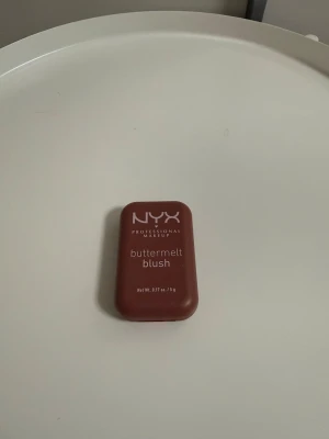 NYX buttermelt blush Feeling Butta - NYX Professional Makeup buttermelt blush i färgen Feeling Butta. Kommer i en kompakt, rektangulär brun plastförpackning med spegel. Rouget har en djup, varm brunröd ton och en sammetslen finish. Perfekt för att ge kinderna en naturlig glow.