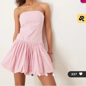 Ljusrosa axelbandslös kortklänning - Superfin ljusrosa kortklänning med axelbandslös design och puffig kjol. Klänningen har smockad rygg och en söt, voluminös nederdel som ger en cool och ungdomlig vibe. Perfekt för dig som vill sticka ut med en feminin och trendig look. Nypris 800kr