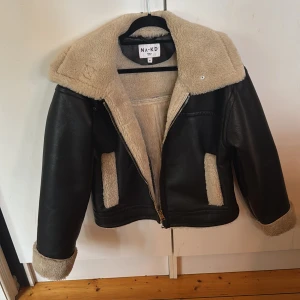 Svart skinnjacka med teddymsterial i från NA-KD, stl 38 - Säljer en svart skinnjacka med teddymsterial i från NA-KD i storlek 38. Jackan har mjukt beige foder och krage i teddy, samt detaljer vid ärmslut och fickor. Yttermaterialet är i skinnimitation och jackan stängs med dragkedja. Perfekt för kalla dagar och riktigt snygg till jeans.