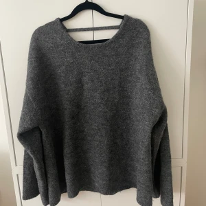 Grå stickad tröja med djup rygg - Grå stickad tröja med djup rygg från Gina Tricot. I ull och alpackamix. Som ny då den endast använts 2 gånger. Kan mötas upp i Sthlm, annars står köparen för frakten 🩷