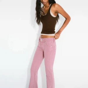 Rosa bootcut jeans från Bershka - Snygga rosa jeans från Bershka med bootcut passform och låg midja. Byxorna har klassisk femficksdesign, silverfärgade knappar och är tillverkade i mjukt bomullsmaterial. Perfekt för dig som vill sticka ut med färg och stil.